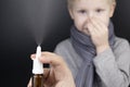 A runny nose is treated with a medicine from a nasal spray. Nasal drops on a black background. Concept for treating a baby cold or