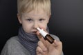 A runny nose is treated with a medicine from a nasal spray. Nasal drops on a black background. Concept for treating a baby cold or