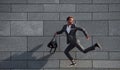 Runs and lating to the job. Young businessman in grey formal wear is outdoors in the city Royalty Free Stock Photo