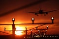 Silhouette of plane landing, runway lights, orange effect Royalty Free Stock Photo