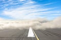 Runway road wrapped in dense low fog, clear blue sky from above. The concept of bad weather at the airport, the delay in the Royalty Free Stock Photo