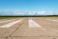 The runway of a rural small airfield against a blue sky with clouds of the airfield. Lonely airfield.