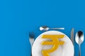 Rupee currency symbol with plate and cutlery