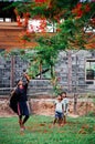 Rural Asian Girl kids and father fun playing under flame tree in summer time