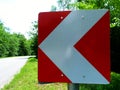 Rural asphalt road with sharp curve ahead road sign in red and white