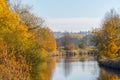 Rural autumnal river scene with blue sky, colorful trees reflecting on the water,swimming Royalty Free Stock Photo