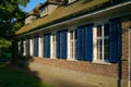 Rural brick wall building with white sash windows with stained glass and blue shutter panels at dusk. Royalty Free Stock Photo