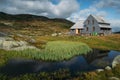 rural cottage house on field with green grass and small pond, Norway, Hardangervidda Royalty Free Stock Photo