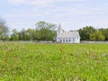 A rural country church with a white fence sits peacefully next to a green pasture. Royalty Free Stock Photo