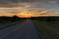 Rural country road leading to a beautiful orange sky at sunset Royalty Free Stock Photo