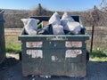 A rural county public waste trash dump for local residents over flowing dumpster