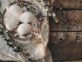 Rural Easter still life. Natural eggs, vintage plate, feathers, pussy willow on rustic table