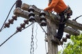 Rural electric poles are being repaired by electricians installing wires to connect. The tops of the electric poles are attached