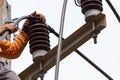 Rural electric poles are being repaired by electricians installing wires to connect. The tops of the electric poles are attached