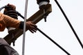 Rural electric poles are being repaired by electricians installing wires to connect. The tops of the electric poles are attached