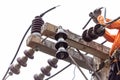 Rural electric poles are being repaired by electricians installing wires to connect. The tops of the electric poles are attached