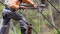 Rural electric poles are being repaired by electricians installing wires to connect. The tops of the electric poles are attached