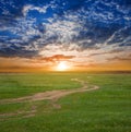 Rural field with ground road at the dramatic sunset Royalty Free Stock Photo