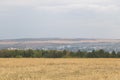 Rural field landscape with distant city and rolling hills Royalty Free Stock Photo