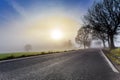 Rural foggy road going to the sunrise