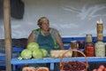 Rural food market. Middle aged woman street seller sitting at the counter, cans with pickles and vegetables on a