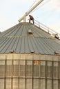 Rural Grain Worker On Top Of Metal Silo