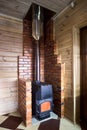Rural home interior element. Cast iron steel wood stove burning warm on floor tile inside brick fireplace, with carbon Royalty Free Stock Photo