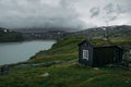 rural house over field with green grass against small pond, Norway, Hardangervidda Royalty Free Stock Photo