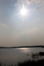 A rural lake landscape with sun rays and sky.