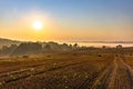 Rural landscape. Colorful sunrise in foggy countryside over agricultural field with harvested wheat Royalty Free Stock Photo