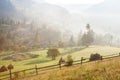 Rural landscape in foggy dawn with wooden fence and haystacks on the meadow in the foreground, Vorokhta, Carpathian Mountains, Ukr Royalty Free Stock Photo