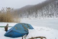 Rural landscape of frozen river and fishing bottom up boat