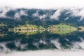 Rural landscape with houses, waterfall and clouds, mirror reflection in the water, Norway Royalty Free Stock Photo