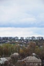 A rural landscape with many private houses and green trees. Suburban panorama on a cloudy afternoon. A place far from the cit
