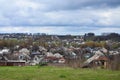 A rural landscape with many private houses and green trees. Suburban panorama on a cloudy afternoon. A place far from the cit