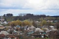 A rural landscape with many private houses and green trees. Suburban panorama on a cloudy afternoon. A place far from the cit