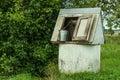 Rural landscape. Old-fashioned well with a metal bucket in the g Royalty Free Stock Photo