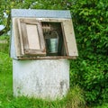 Rural landscape. Old-fashioned well with a metal bucket in the g Royalty Free Stock Photo