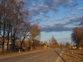 Rural landscape. A road leading into the distance, trees along the edges and a blue sky with clouds Royalty Free Stock Photo