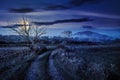 rural landscape with road to mountain through rural field behind the wooden fence Royalty Free Stock Photo