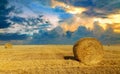 Beautiful sunset over farm field with many hay bales with blue sky and colorful clouds in background. Royalty Free Stock Photo
