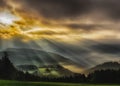 Foggy epic glorious sunrise over a countryside with hills,fields, trees,dramatic sky