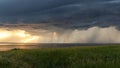 Rural landscape. Storm clouds over the lake at sunset. Green fields and meadows. Golden sunset Royalty Free Stock Photo