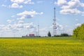 Rural landscape. Telecommunication tower on a yellow rape field, a small country house with a red roof Royalty Free Stock Photo