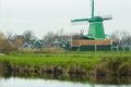 Rural landscape with traditional Dutch windmill and old farm houses on riverbank Royalty Free Stock Photo