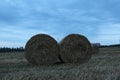 Rural landscape two haystacks bales of hay straw lying on a field close up in warm or cold light