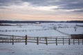 The rural landscape is a winter evening. A horse farm without horses. Wooden fences fence for walking horses Royalty Free Stock Photo