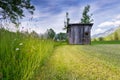 Rural meadow with high grass and old wooden hut Royalty Free Stock Photo