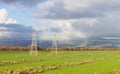 Pylons standing in open farmland carrying electricity.