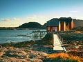 Rural Norwegian landscape, traditional red and white wooden house on rocky island. Suny spring day with smooth water